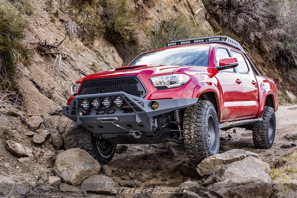 Red Toyota Tacoma Crawling over some rocks