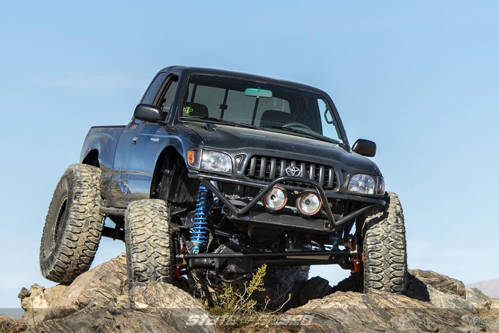 Blue Toyota Tacoma crawling down a rocky hill