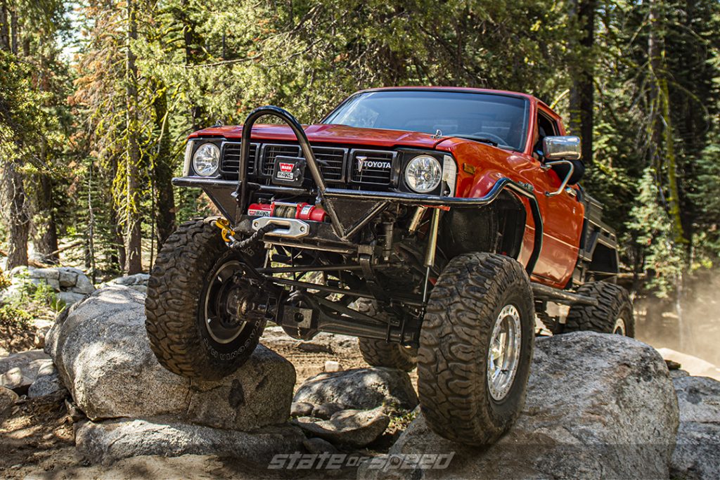 custom orange toyota hilux crawling over rocks in forest on patagonia M/T Tires