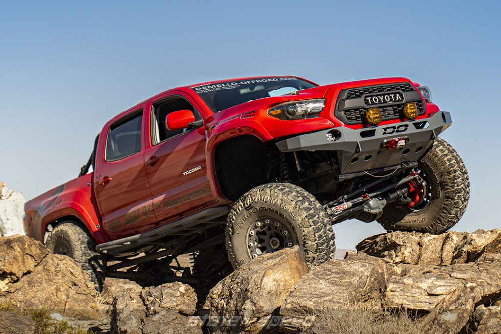 red toyota tacoma crawling over rocks