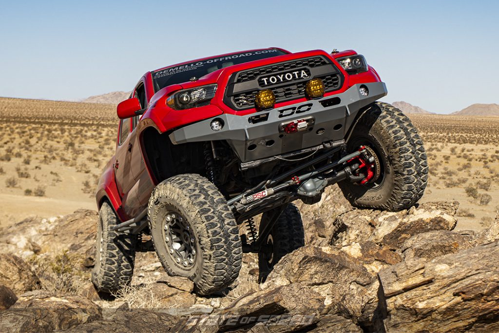 red toyota tacoma crawling over rocks