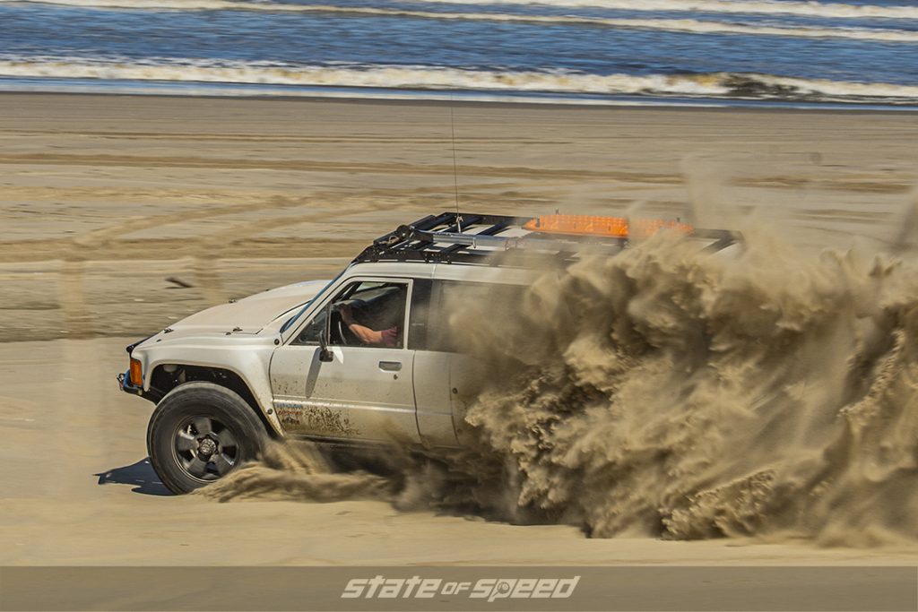 white toyota pick up tears up the sand on an Oregon beach