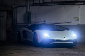 The Lamborghini parked in the garage with its headlights on