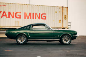 Side view of the Green 1965 Mustang Fastback 2+2 next to a shipping container